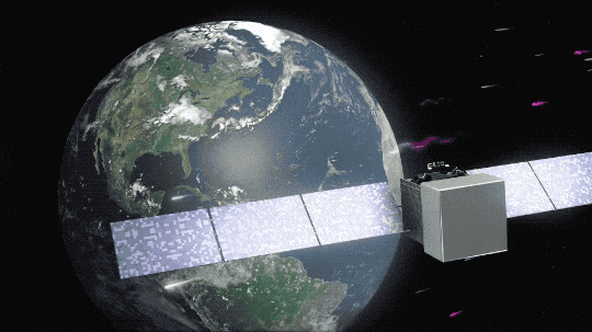 Earth turns slowly in the background of this animation as the Fermi spacecraft flies in its orbit. Fermi is a shaped like a large gray box with long, blue solar panels extending from either side of the box. Particles and gamma rays, shown as squiggles of gray and magenta, respectively, fly from right to left across the screen, with a few gamma rays getting detected by Fermi.
