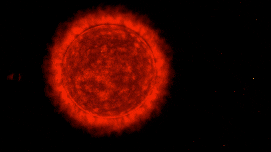 A red, glowing star starts out small and starts to grow, eventually taking up the entire frame. As the star grows, a small planet first skims the surface of the star on the left, creating a fiery skid mark. But then the star overtakes the planet, engulfing it completely in a small orange blip.