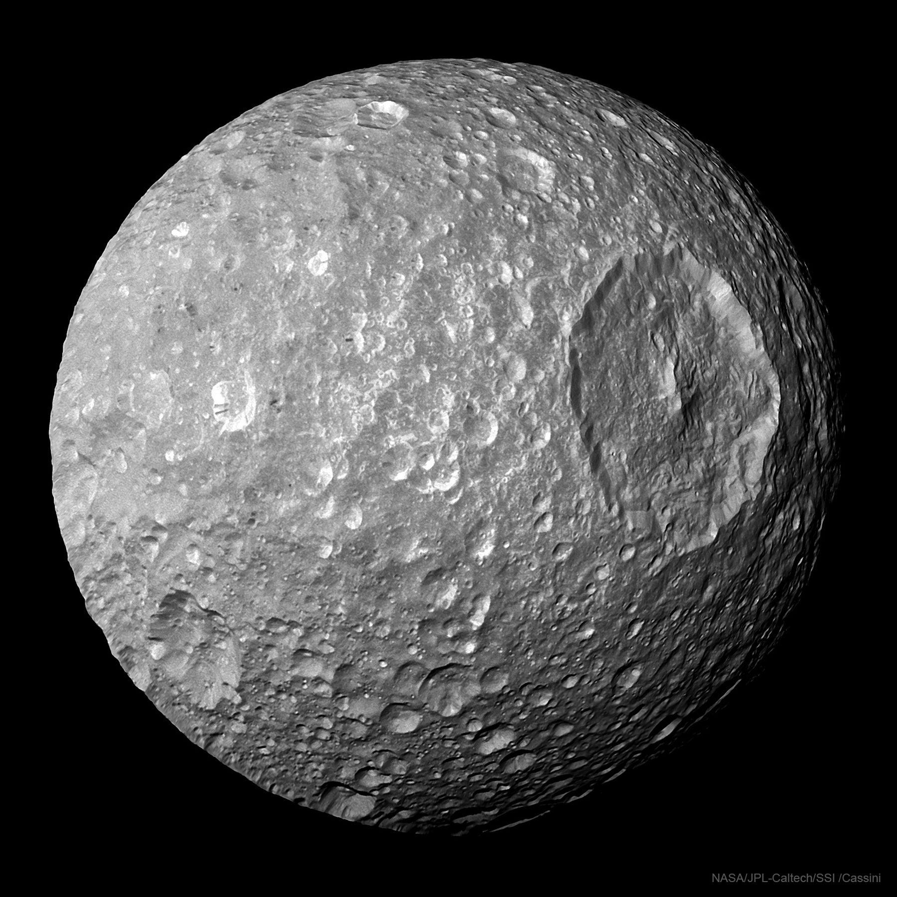 The picture shows Saturn's Moon Mimas featuring a very large circular crater. Please see the explanation for more detailed information.