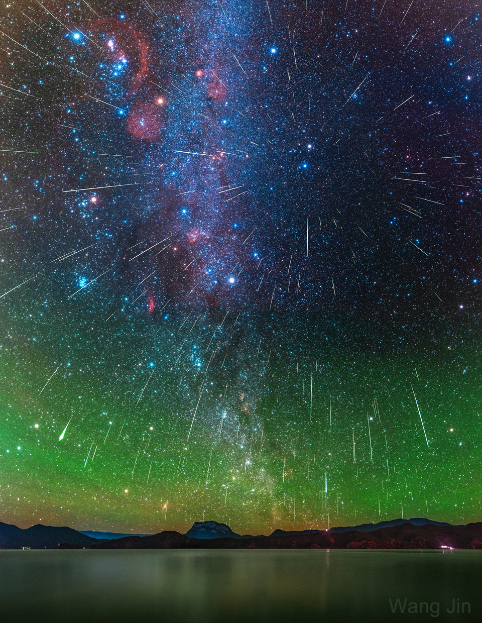 The picture shows a composite of over 200 Geminid meteors from the 2020 Geminids meteor shower over Lake Lugu in Yunnan, China. Please see the explanation for more detailed information.
