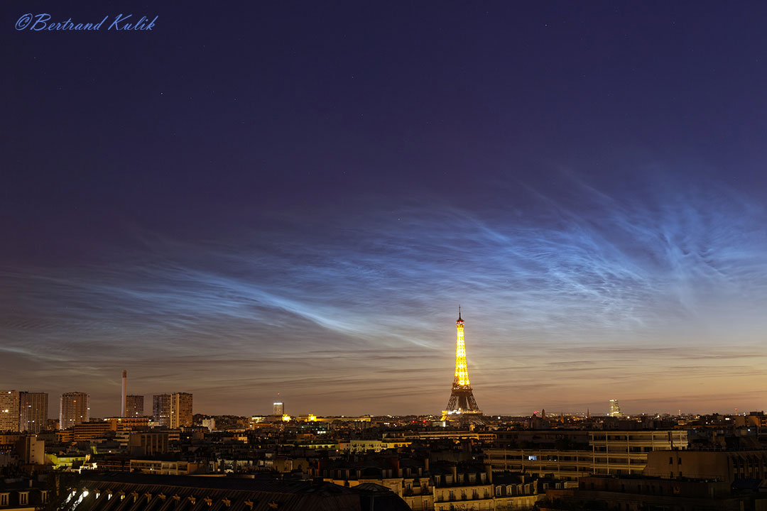The featured image shows the Eiffel tower in Paris, France below a wide display of glowing noctilucent clouds. Please see the explanation for more detailed information.