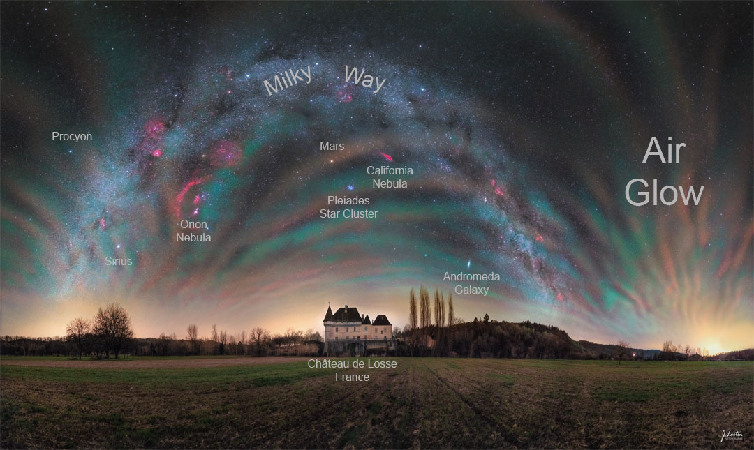 The sky over a picturesque chateau in France is shown featuring colorful airglow all around. Identifiable in the background night sky are objects that include the Orion Nebula, Sirius, Mars, and an arching band of our Milky Way Galaxy. Please see the explanation for more detailed information.