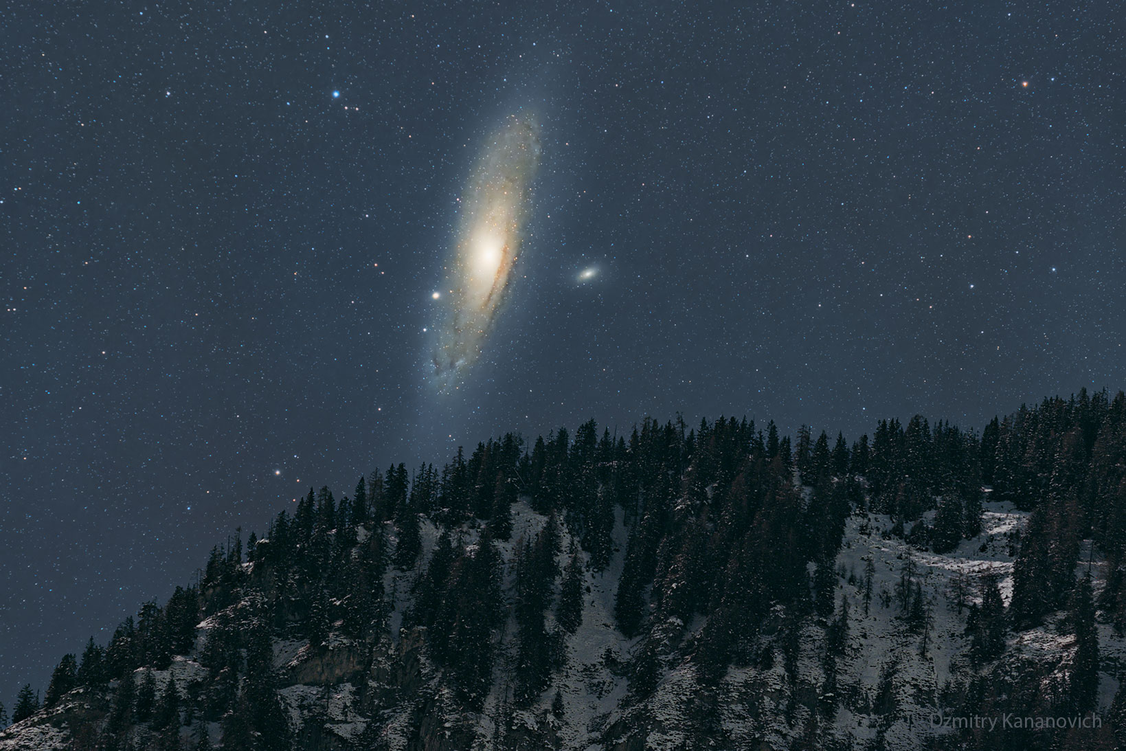 The night sky over a snowy mountain is shown, with the dark sky dominated by a large spiral galaxy -- the Andromeda galaxy. Please see the explanation for more detailed information.