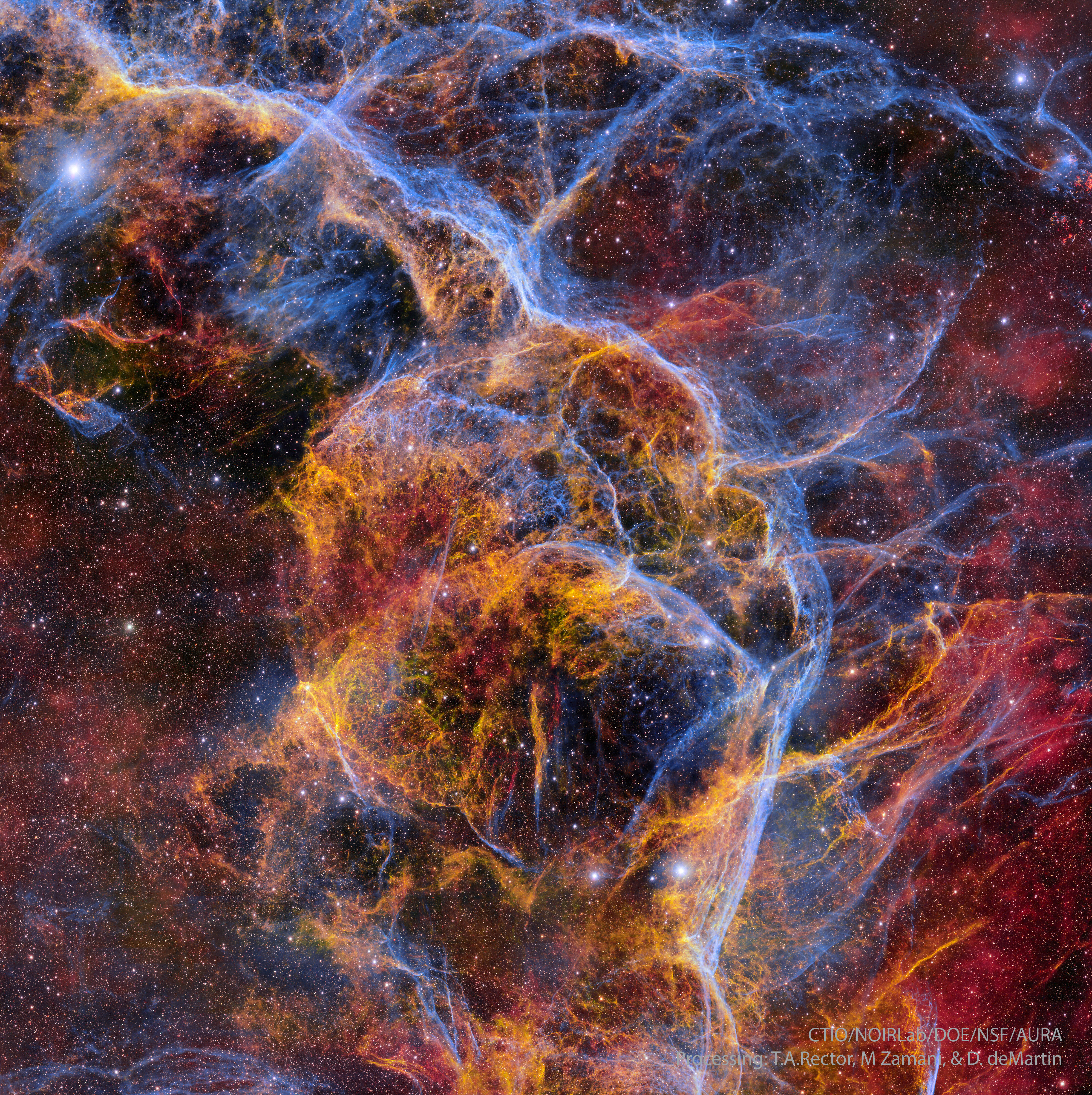 Complex filaments of many colors cross the image in front of a starry background. Some regions have a diffuse red or orange glow. Please see the explanation for more detailed information.