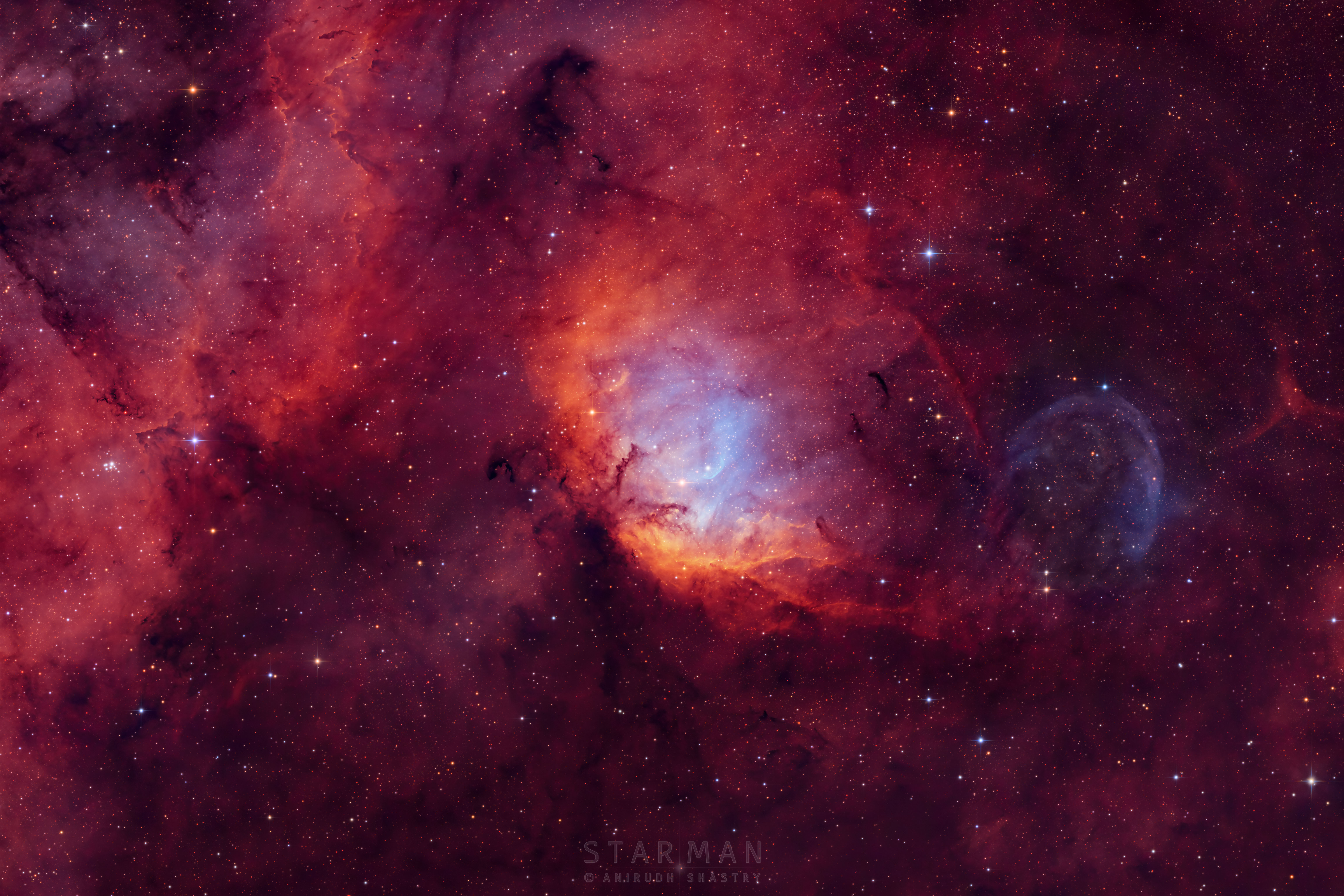 A picture of a starfield with red emission nebulae is shown. Toward the right is a point of light that is Cygnus X-1, a nearby black hole. Above the black hole is a blue-shaded bow shock wave in the surrounding gas. Please see the explanation for more detailed information.