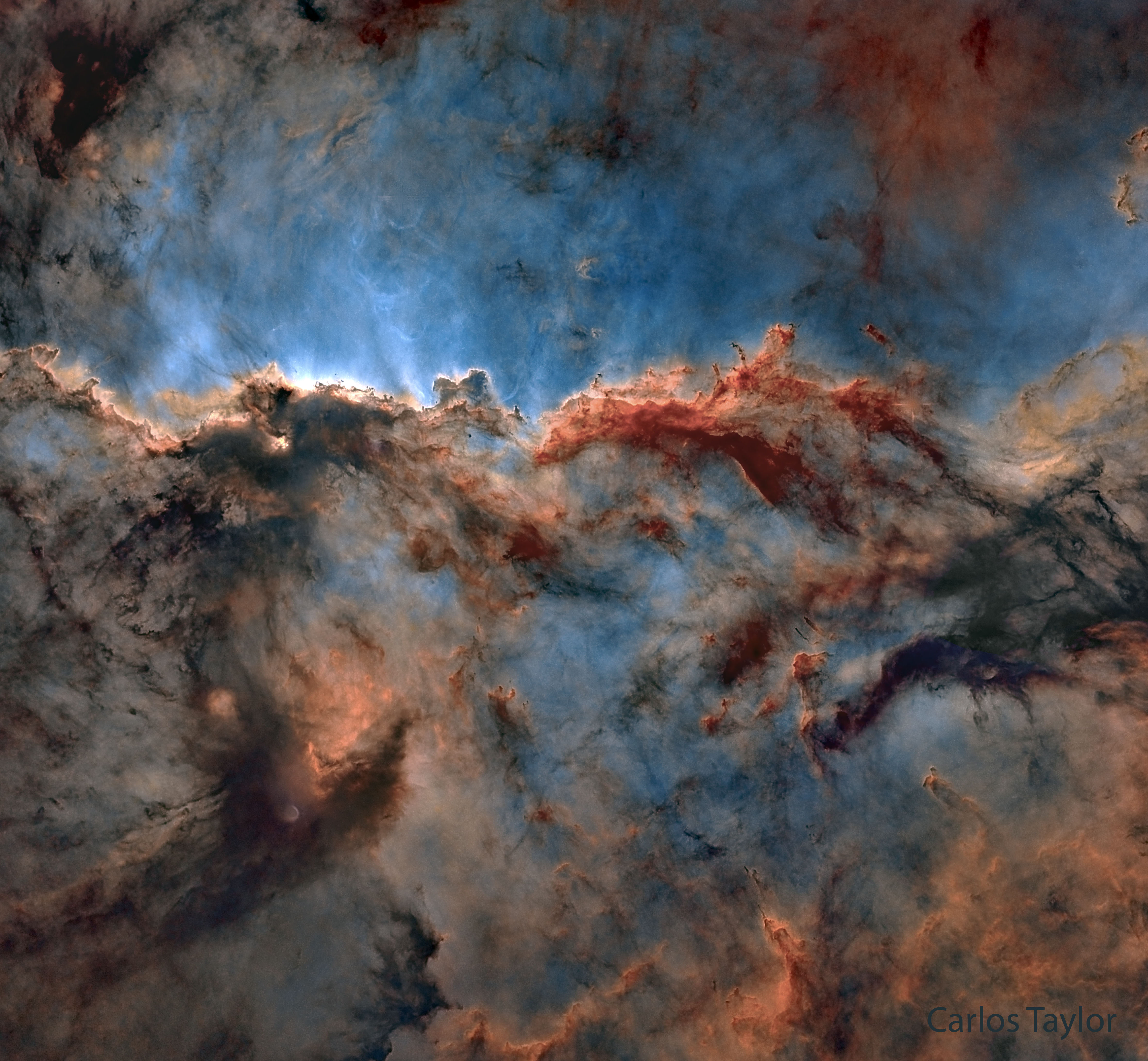 Gas and dust are shown in a deep starfield. The gas glows blue and red, while the dark dust is connected in filaments across the image. To some, the filaments appear to have the shape of two dragons fighting. Please see the explanation for more detailed information.