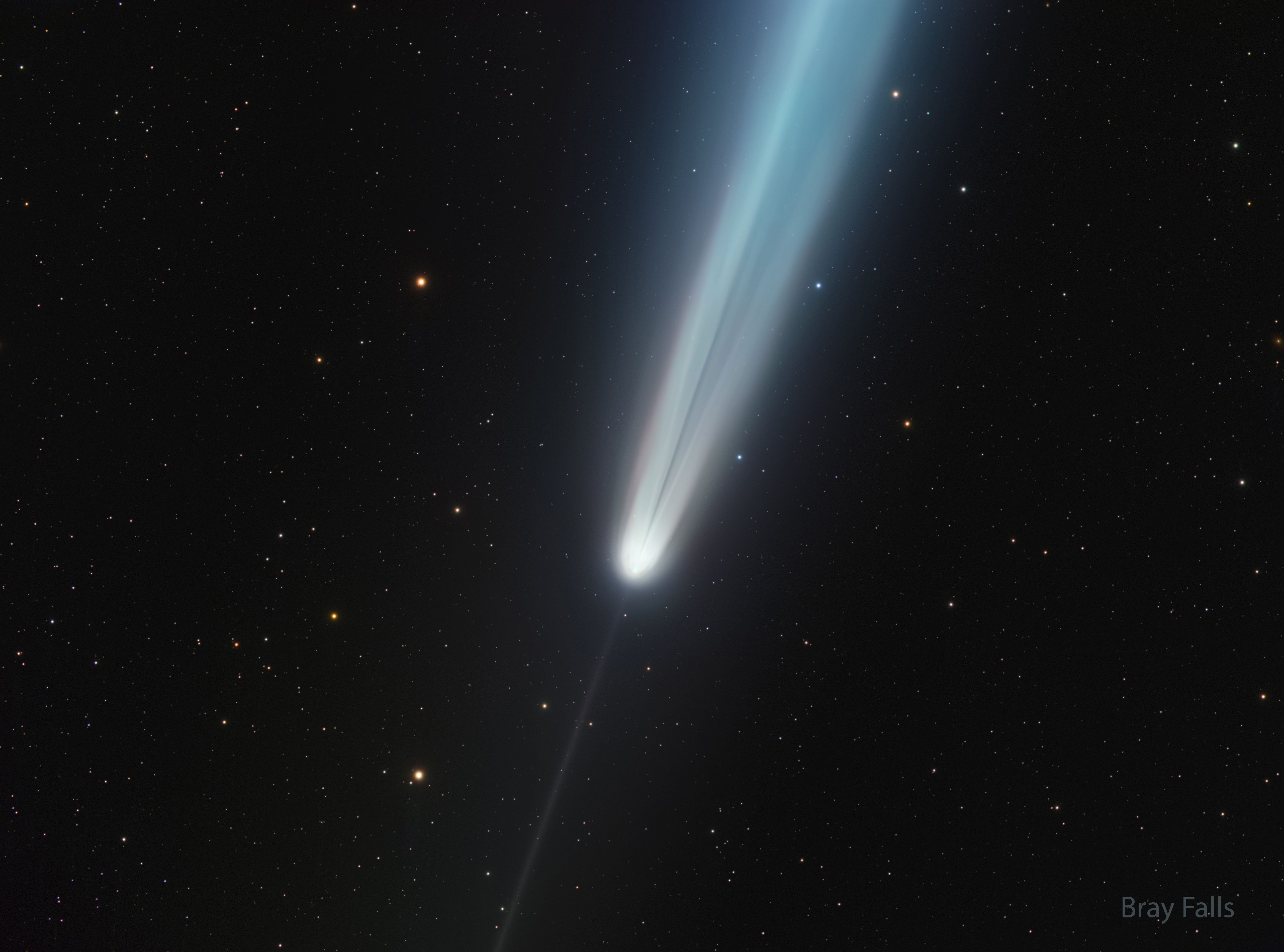 A starfield is shown that includes a bright comet. A bright tail points to the upper right but has an unusual dark streak in it. A thin anti-tail points toward the lower left. Please see the explanation for more detailed information.