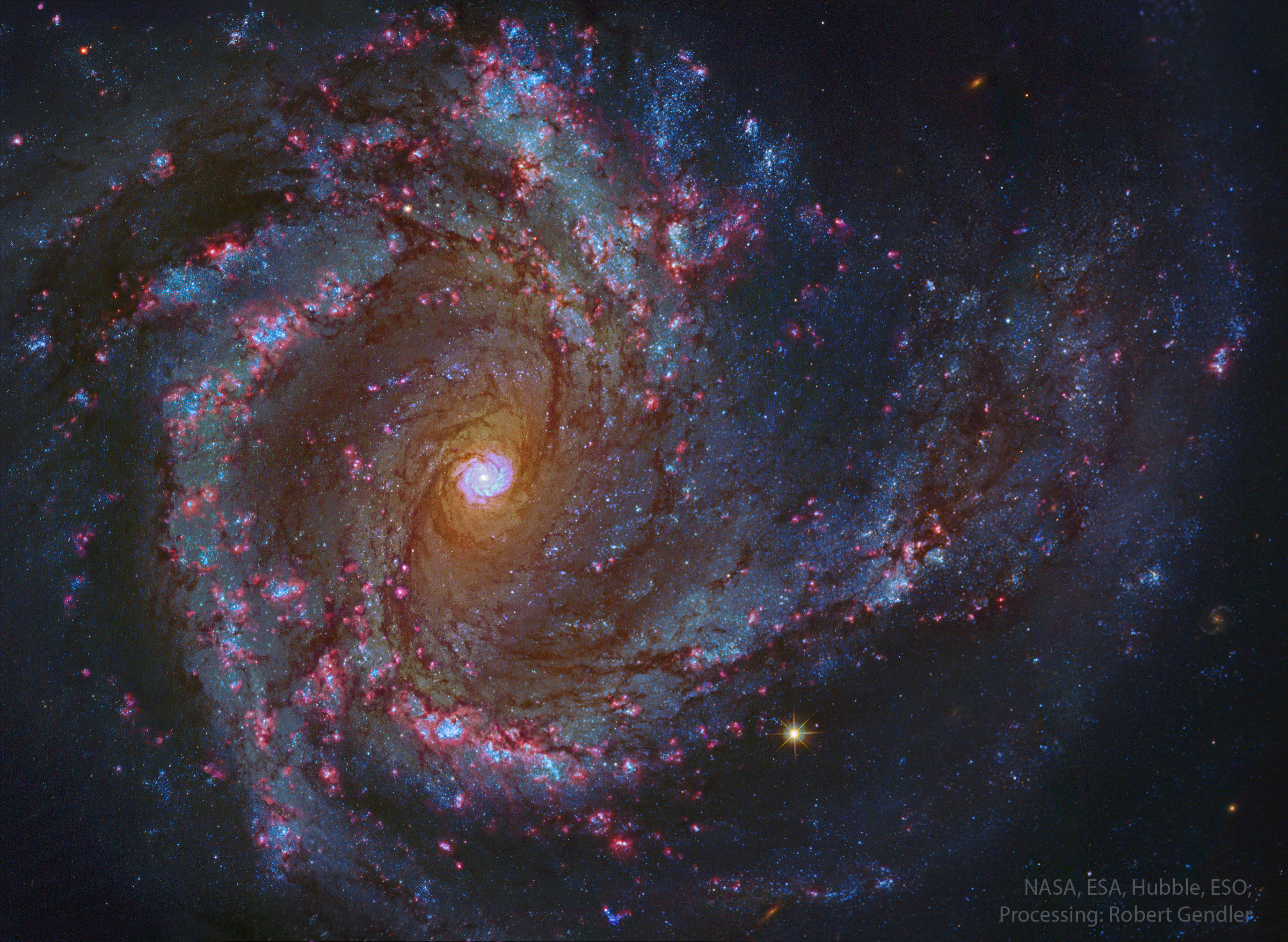 A sprawling spiral galaxy is shown in great detail. This galaxy has blue spiral arms and a bright center that itself seems to look like a spiral galaxy. Please see the explanation for more detailed information.