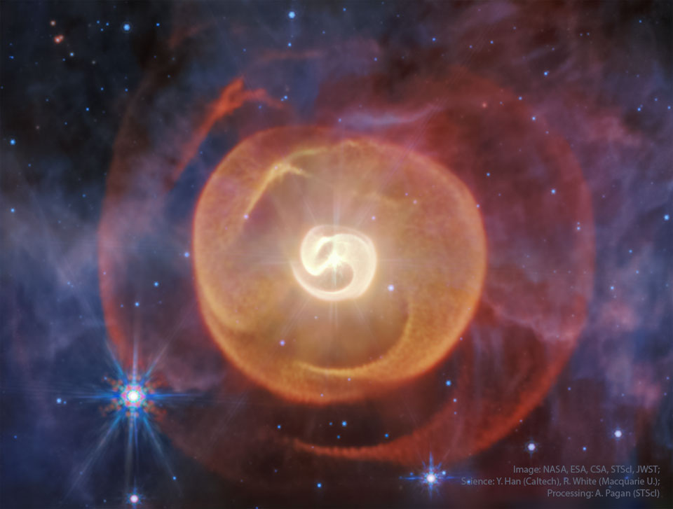 A starfield has a large and unusual red and orange nebula in the middle. The nebula seems to contain not only swirls but also nearly transparent shells. Please see the explanation for more detailed information.