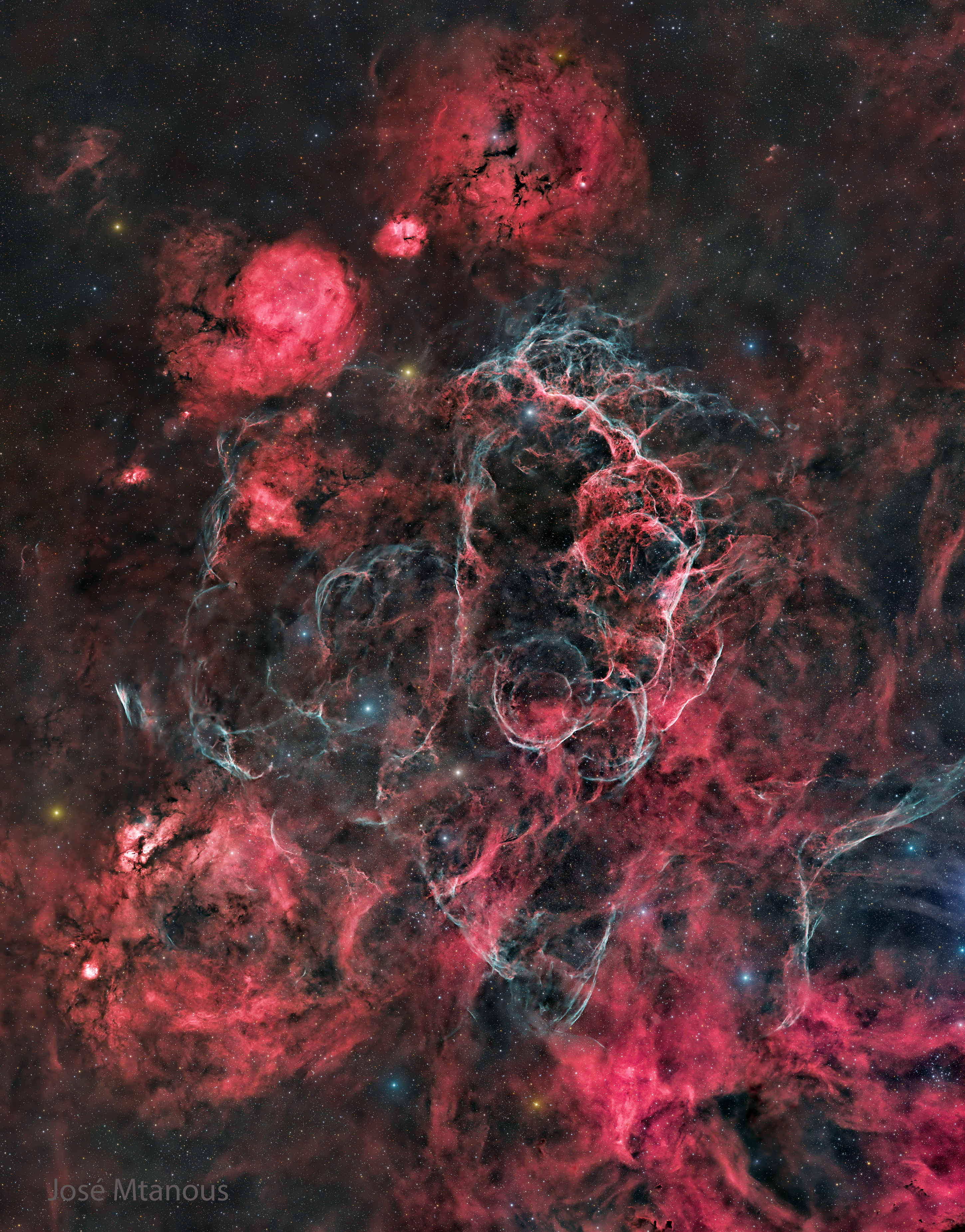 The starfield is filled with many red nebulas, areas of dark dust, and light blue filaments. Please see the explanation for more detailed information.