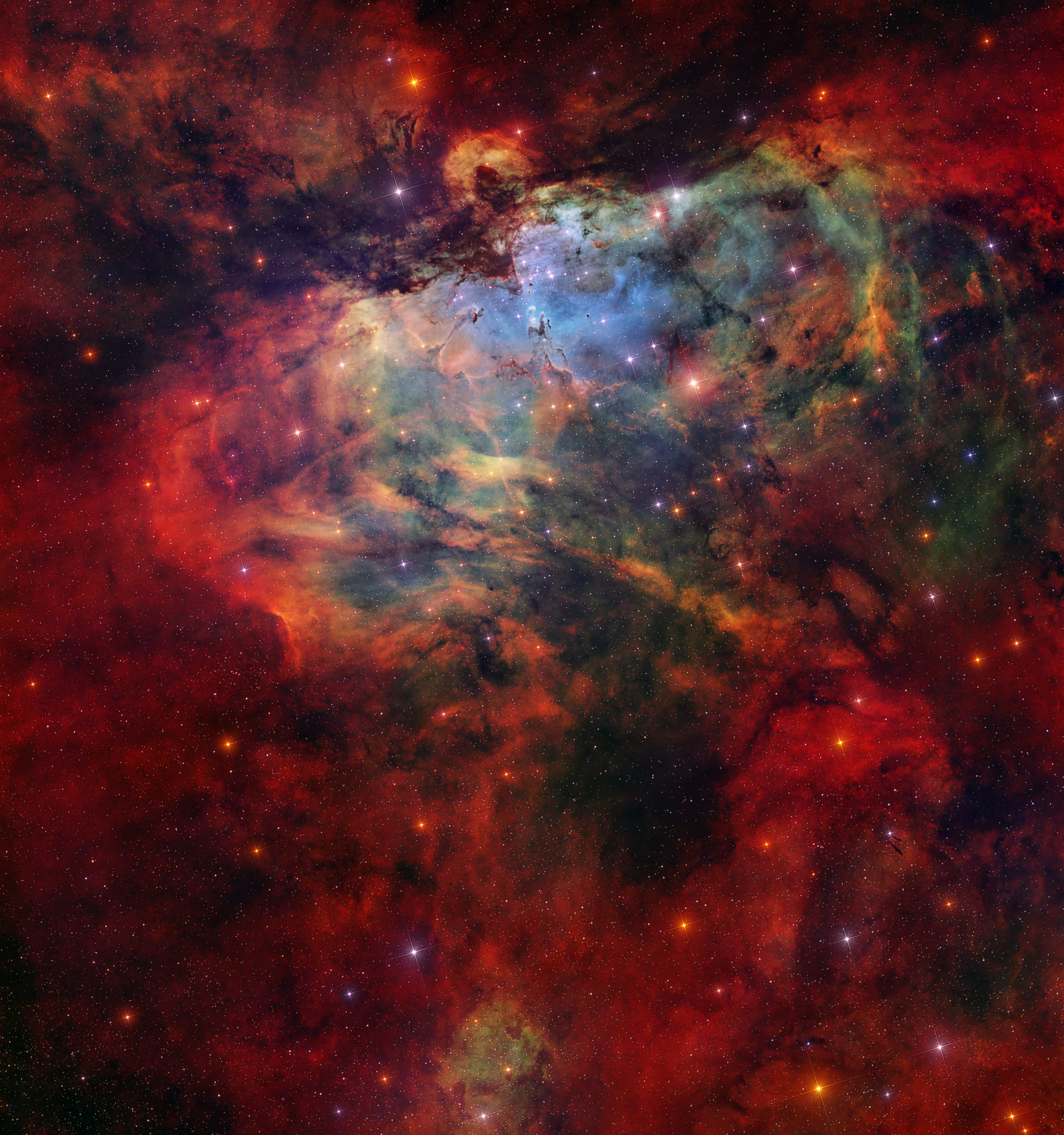 Gas, dust, and stars are scattered across the image. A dark silhouette that looks like an eagle swoops downward towards three small pillars of gas. Other gas and dust pillar-like features reach out of the surrounding nebula. A central cluster of stars sits beneath the eagle silhouette.