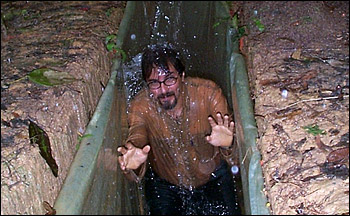 Photograph of researcher getting drenched in trench dug around Amazon research site