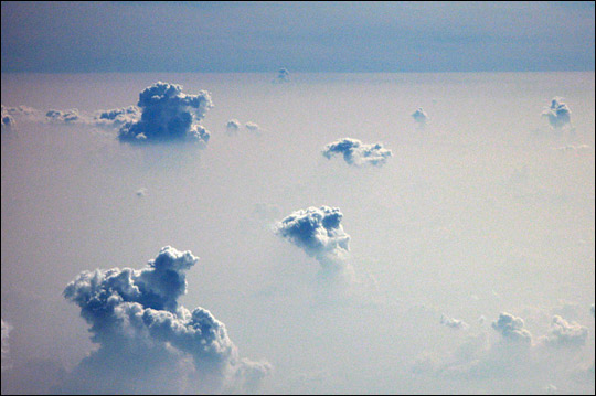 Photograph of cumulus clouds poking through a smoke layer above the Amazon.