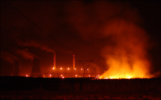 Photographs of flames from a night-time brushfire underneath South African power lines.