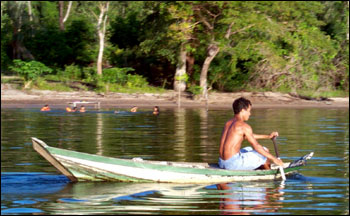 Photograpg of a Boy Paddling A Boat Through the Jungle