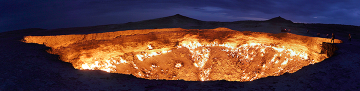 Bystanders watch as natural gas burns alongside a crater, caused by natural gas drilling.