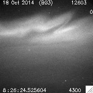 A black and white video of a night sky showing flickering auroras and a background of stars. It includes a date and time stamp.