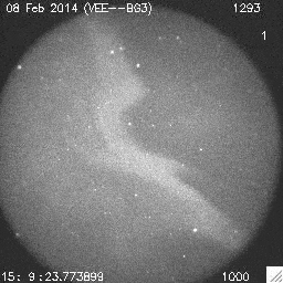 A black and white video of a night sky showing pulsating auroras and a background of stars. It includes a date and time stamp.