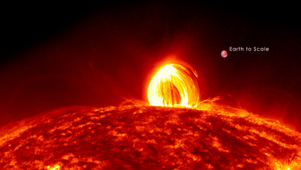 A solar prominence arcs above the sun's surface, with Earth shown to scale for size comparison.