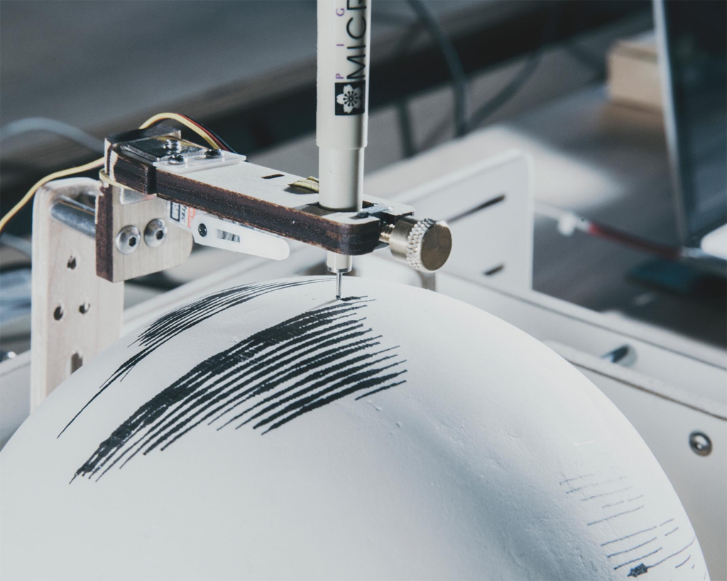 A pen draws collection annual Landsat collection patterns on a plaster globe.