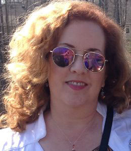 Photograph of a woman with red hair wearing sungalsses.