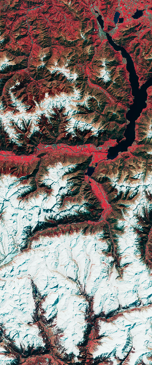 False-color Landsat satellite image showing bare land among forested slopes forming the number 3.