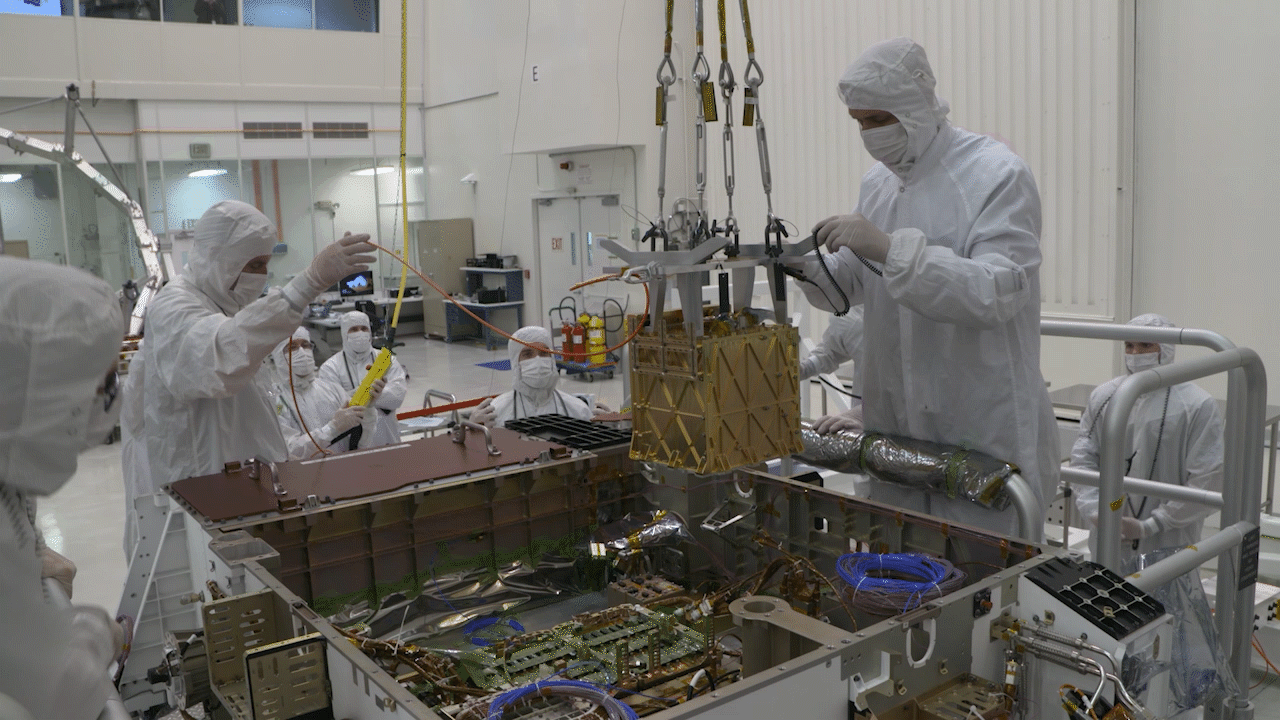 NASA Technicians the MOXIE instrument into the belly of the Perseverance rover