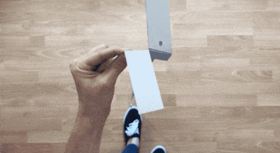 An animation of a person dropping a paper helicopter which then spins as it falls to the wooden floor.