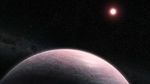 A reddish, terrestrial exoplanet is seen in orbit of its red dwarf star.