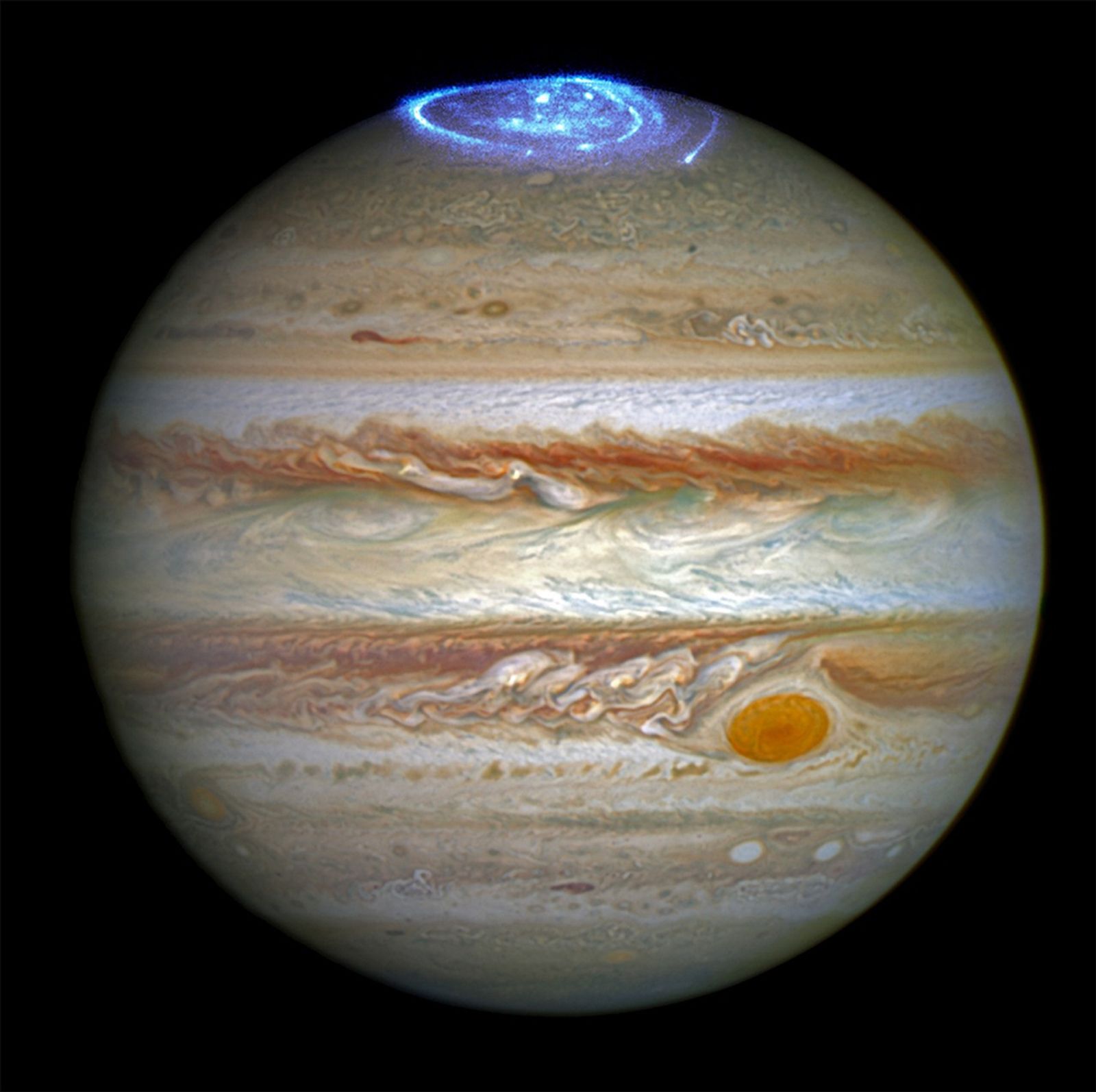 Jupiter is topped with a glowing blue aurora in this enhanced, full-disk image of the gas giant planet.