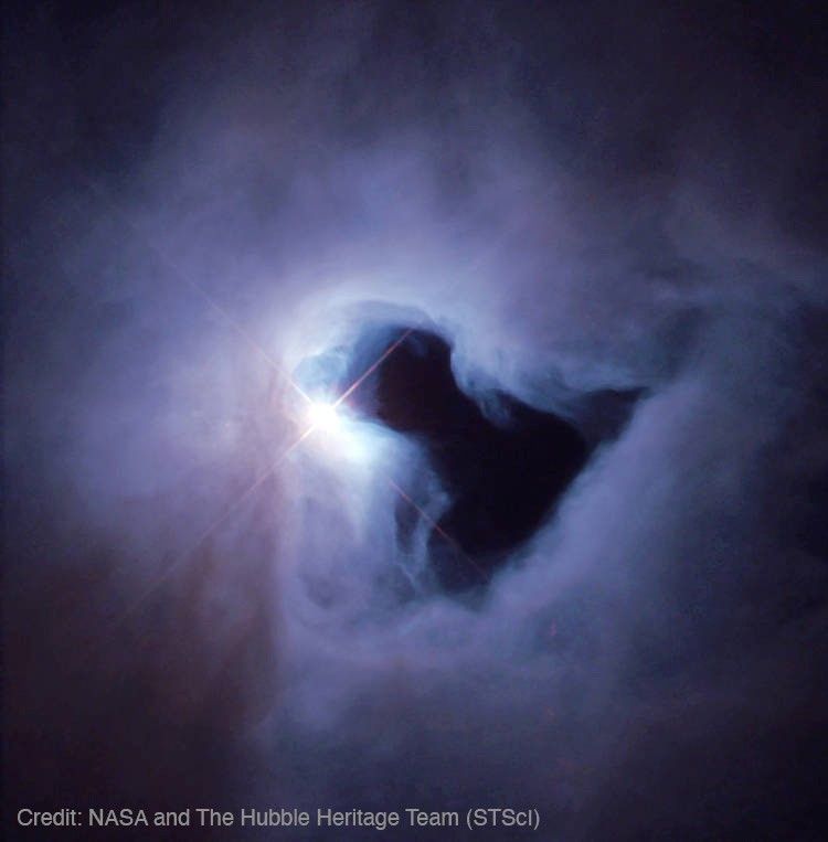 A gray haze fills most of the frame with a large black region in the shape of a game pawn tilted about 45-degrees to the left. Credit: NASA and The Hubble Heritage Team (STScI)