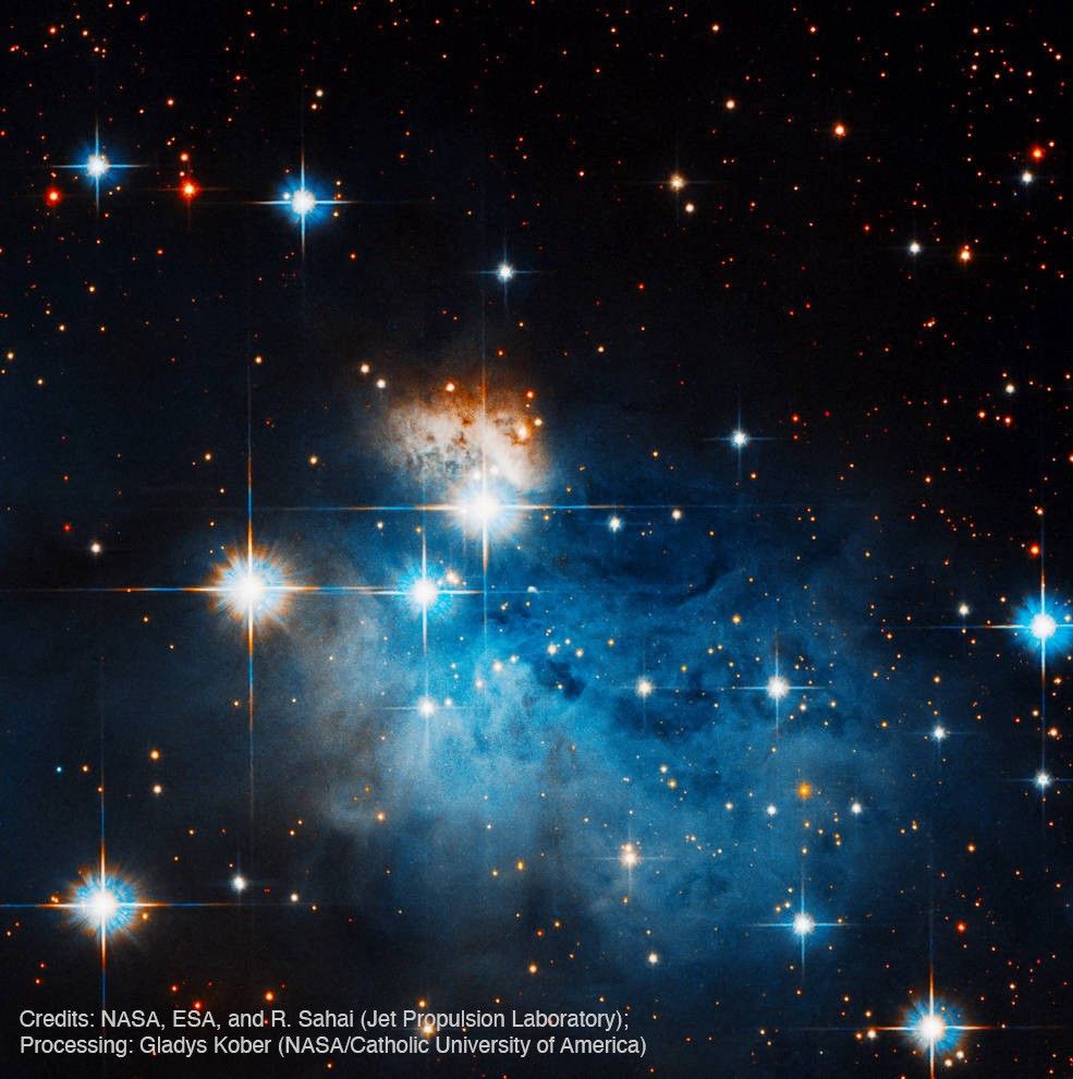 Against a starry background, this nebula looks like a flowing dress with a reddish-white bodice and flowing faint blue skirt. In the foreground are a few bright stars, each having four rainbow spikes. Credit: NASA, ESA, and R. Sahai (Jet Propulsion Laboratory); Processing: Gladys Kober (NASA/Catholic University of America)