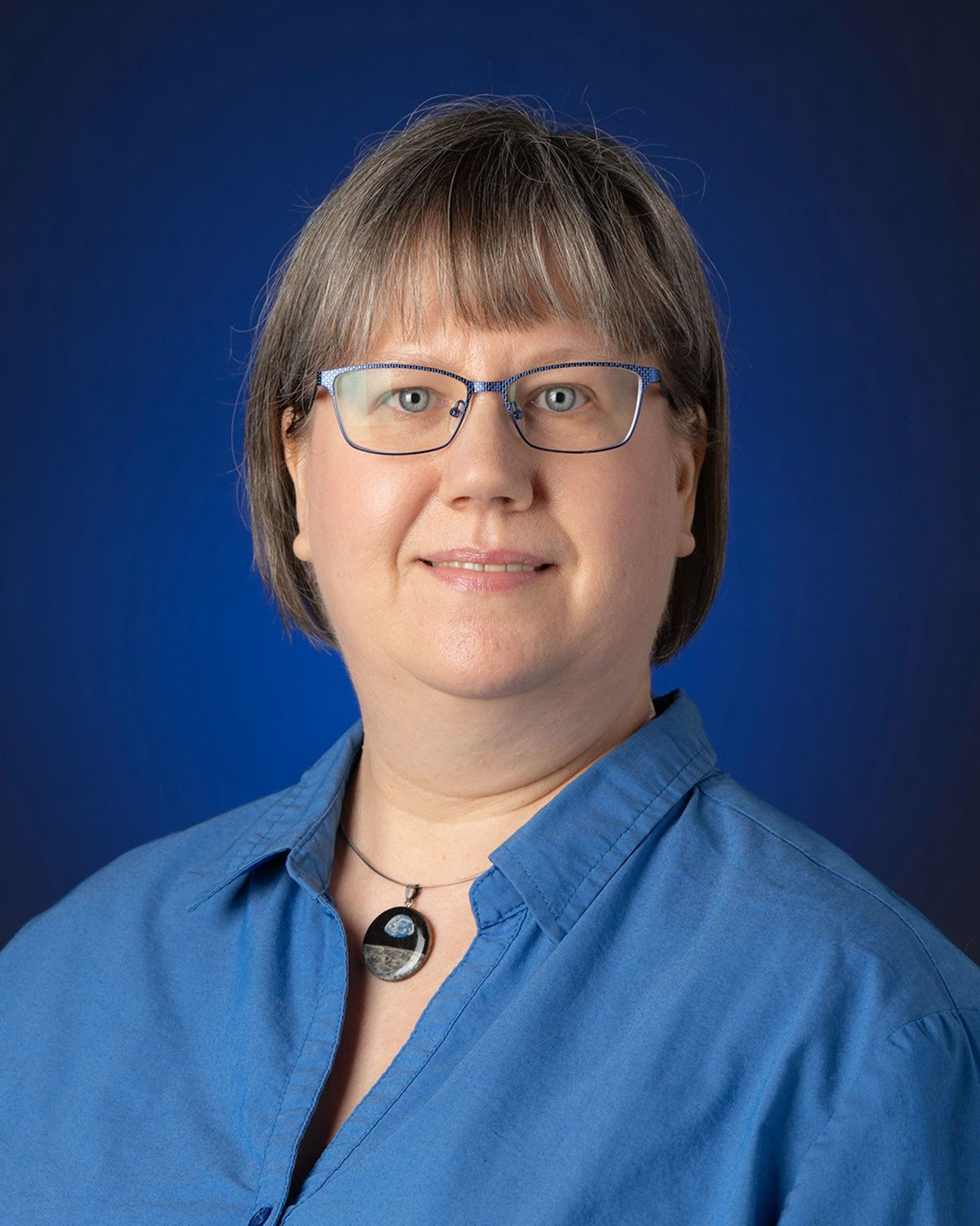 Portrait photo of a woman wearing glasses and a blue shirt