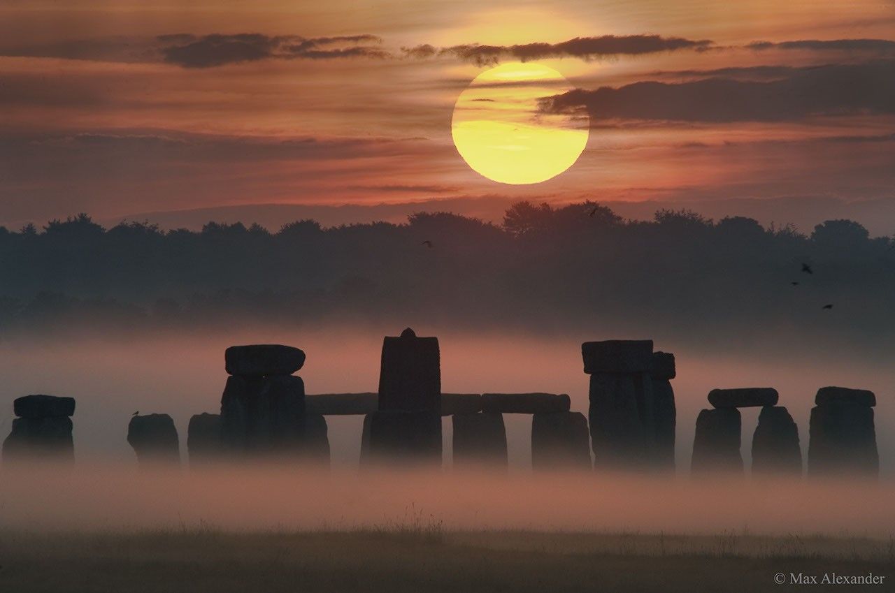 The picture shows the Sun rising over the blocks of Stonehenge. Please see the explanation for more detailed information.