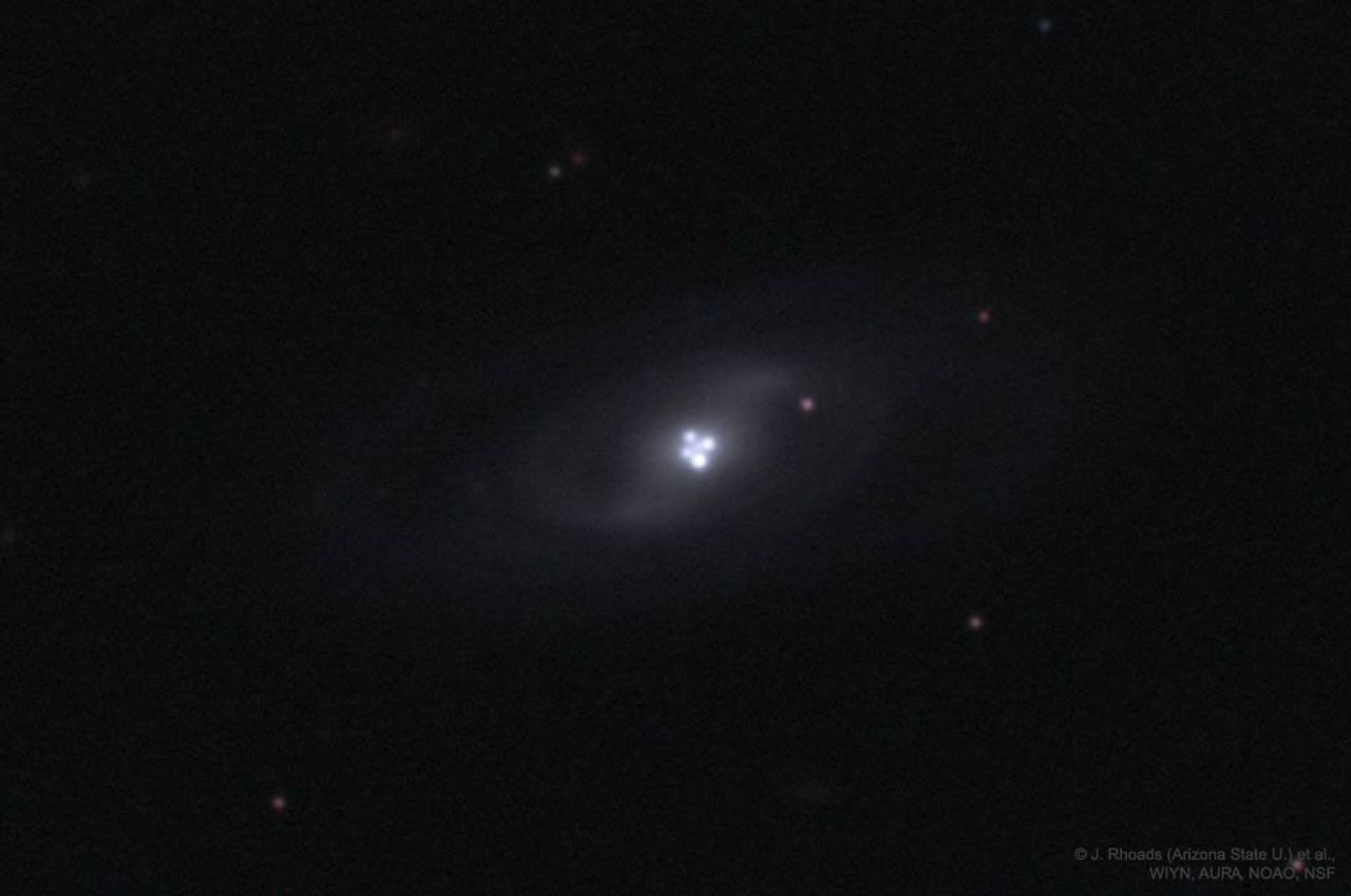 The picture shows single distant quasar that appears four times due to the gravitational lens effect of an intervening galaxy. Please see the explanation for more detailed information.