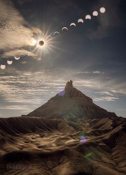 A sequence of Sun and Moon images are shown behind a scenic foreground that features the large Factory Butte. The foreground was taken during the maximum part of the annular eclipse and seems somehow oddly lit. Please see the explanation fo