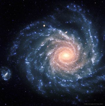 A spiral galaxy with big blue spiral arms is shown with a center that appears more yellow. Please see the explanation for more detailed information.