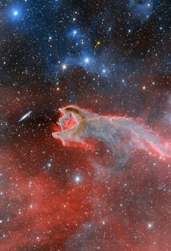 The featured image shows a distant galaxy on the left next to a gas cloud on the right. An opening in the gas cloud is on the same side as the galaxy. Please see the explanation for more detailed information.