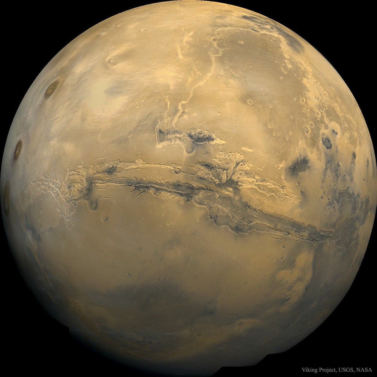A picture of Mars is shown as a large orange globe. Across the center of the planet a long canyon is visible. Please see the explanation for more detailed information.