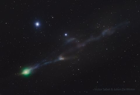 A starfield is shown around a comet. The green coma of the comet is on the lower left. A meandering blue-tinted tail goes off to the upper right. A slight anti-tail is seen from the coma toward the lower left. Please see the explanation for