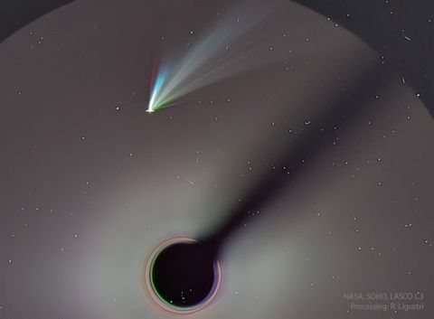 A comet is seen near the top of the image. The comet has several tails visible, some being white but others having different colors. Please see the explanation for more detailed information.