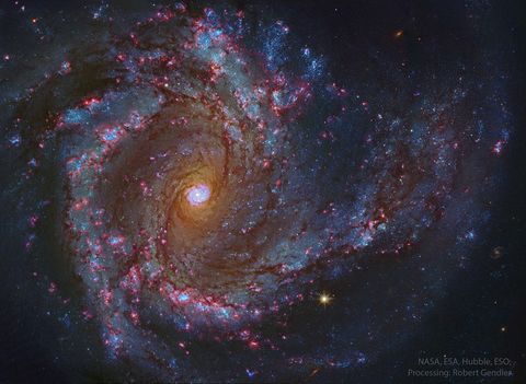 A sprawling spiral galaxy is shown in great detail. This galaxy has blue spiral arms and a bright center that itself seems to look like a spiral galaxy. Please see the explanation for more detailed information.