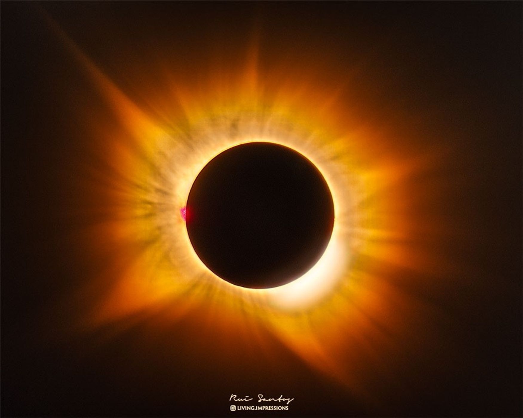 A total eclipse Sun is featured in the image center. Around the Sun is a filamentary gold-hued corona flowing out in all directions. Please see the explanation for more detailed information.