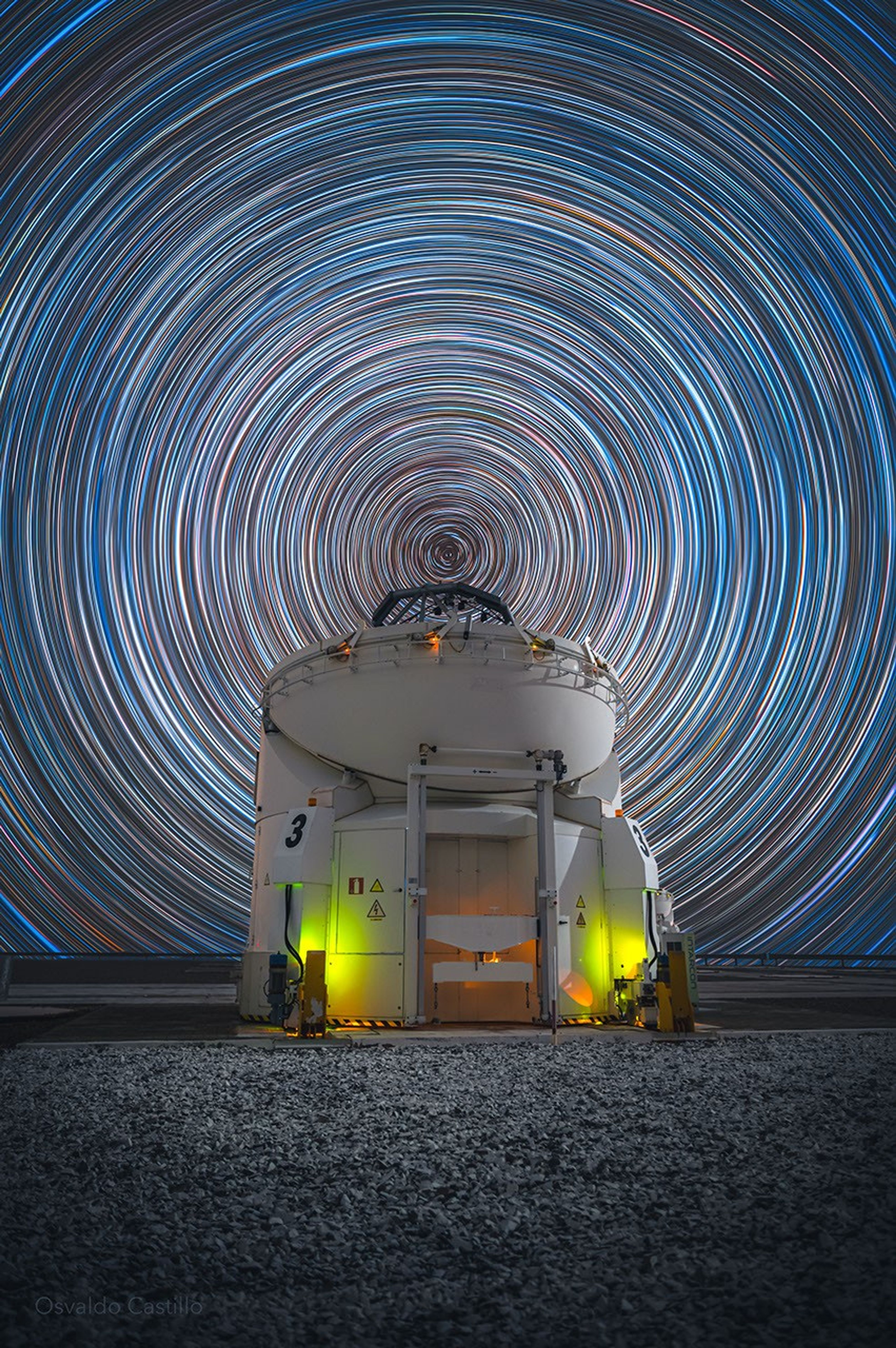 A picture of star trails in the night sky above a telescope.