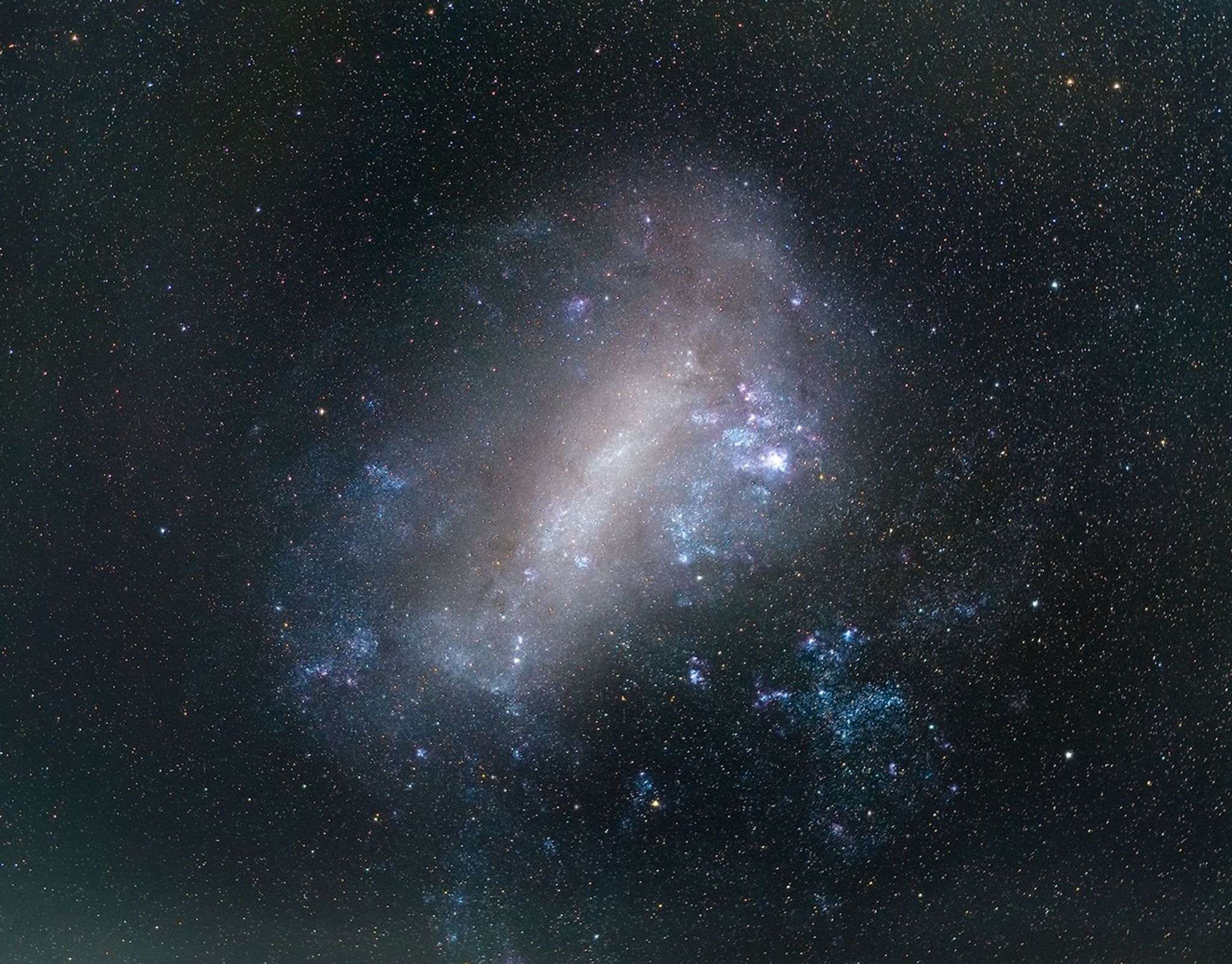A galaxy with stars and colorful clouds of gas.. The background is a dark field of stars.