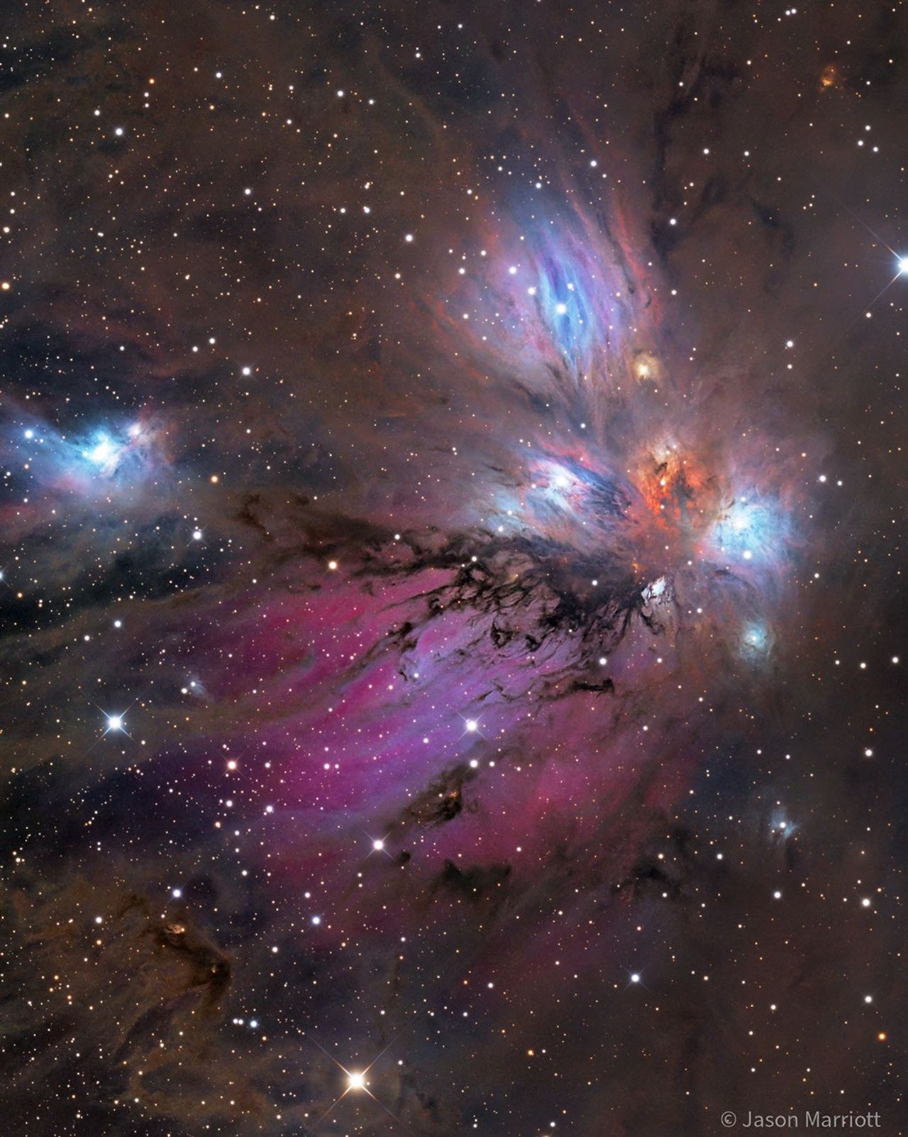 A starfield surrounds a colorful nebula that glows both red and blue but is filled with dust, both light brown and dark brown. Please see the explanation for more detailed information.