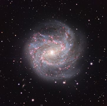 A spiral galaxy is shown in front of a dark field of stars.