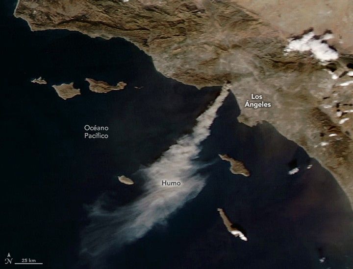 Imagen de satélite de la NASA del humo del incendio de Palisades en enero de 2025. A la derecha se ve la costa de California. Una larga columna de humo gris se extiende desde la zona de Los Ángeles hasta las aguas azul oscuro del océano Pacífico.