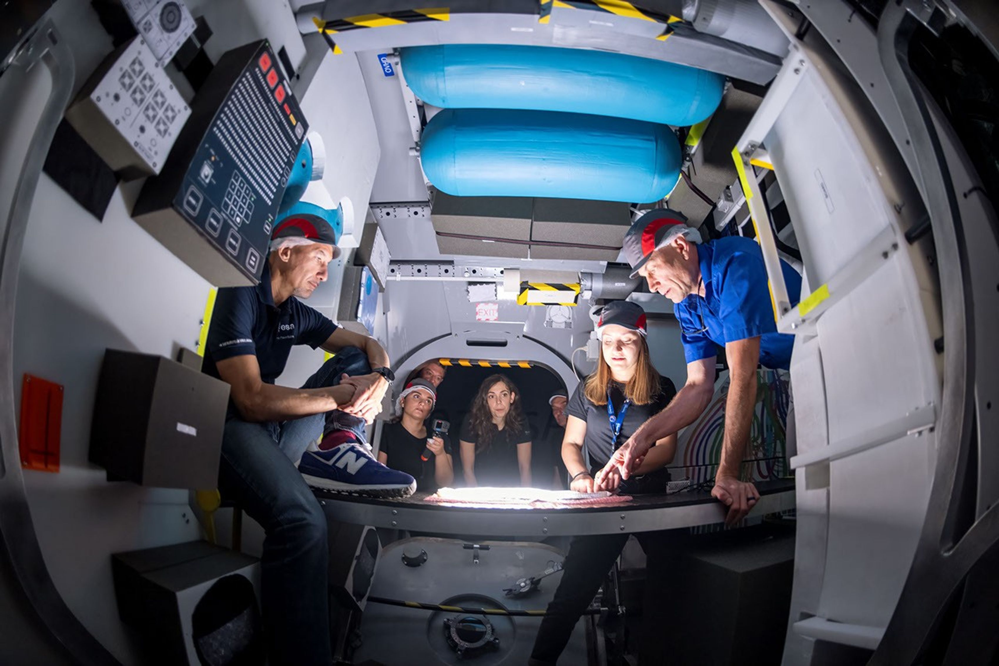 Equipos de la NASA y la ESA (Agencia Espacial Europea), entre ellos el astronauta de la NASA Stan Love (extremo derecho) y el astronauta de la ESA Luca Parmitano (extremo izquierdo) ayudan a realizar pruebas de factores humanos dentro de una réplica de la estación espacial lunar Gateway.