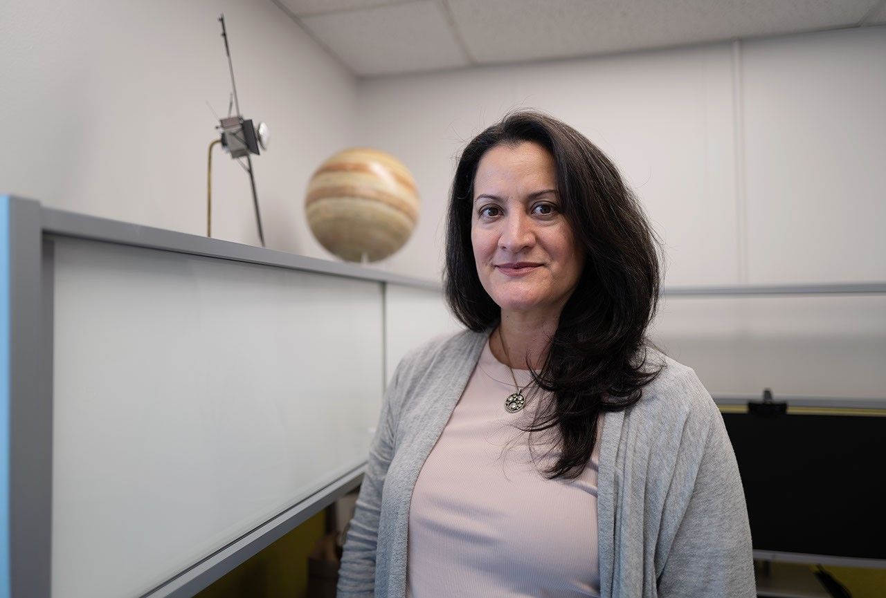 Dr. Delia Santiago-Materese in her office. A model of Jupiter and the Juno spacecraft rest on a shelf on the left.